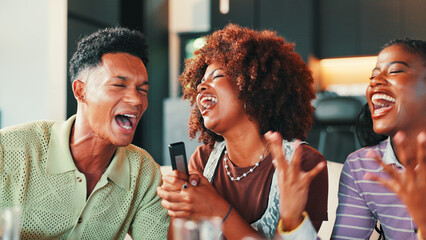 Karaoke, microphone and friends singing in home for celebration, laughing and bonding at social gathering. Singer, group and people in living room for song with music, entertainment and fun at party
