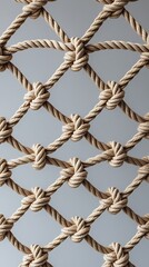 Close-up of beige rope netting, showing detailed texture and pattern of knotted ropes arranged in a diamond grid against a neutral background

