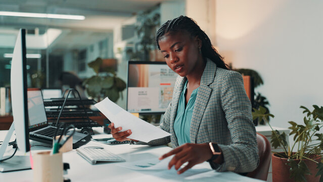 Black woman, documents and reading by computer in office for project, admin and review for proposal. Person, paperwork and pc for research, planning and feedback for perspective at creative agency