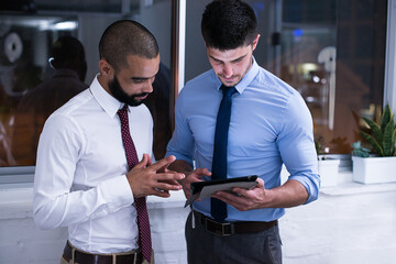 Businessmen, meeting and coaching with tablet, talking about company project at night in office....