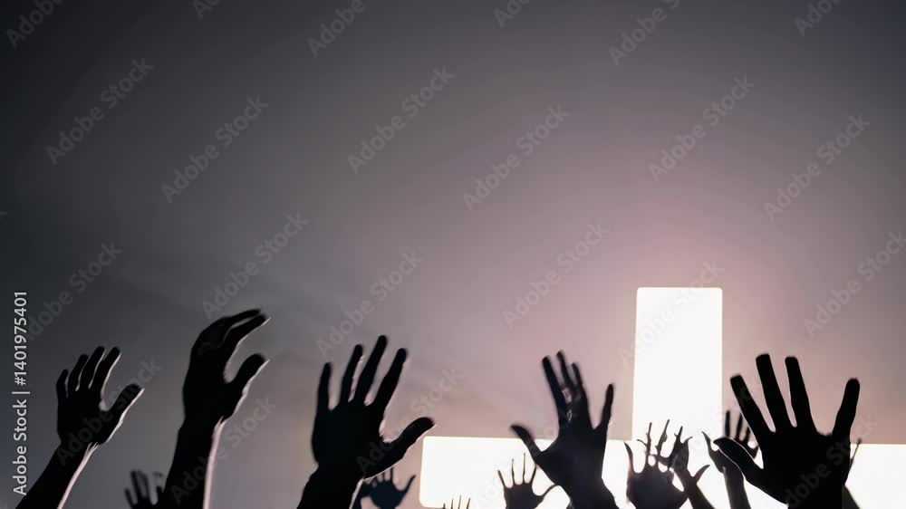 Poster silhouetted crowd with raised hands in front of a glowing cross, captured from a low angle, creating