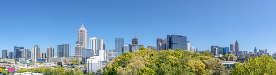 Downtown, Midtown Atlanta Skyline showing several prominent buildings, highways, cars and hotels under a blue sky.