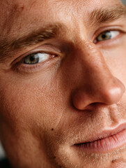 Subtle Smile and a Watchful Gaze – Close-Up of a Light-Eyed Man with Fine Stubble and Calm Expression