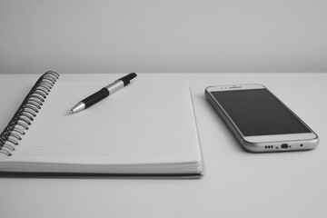 Notebook, pen, and phone on table