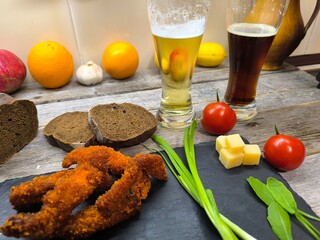 Pieces of beautiful nuggets lie on a sliced board next to glasses of beer