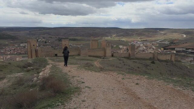 Person walking towards ancient castle wall in Molina de Aragon