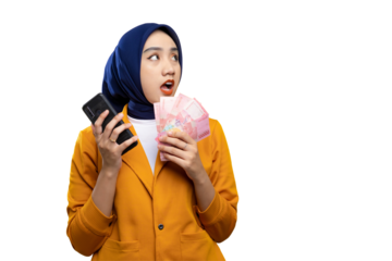 Shocked young Asian woman holding money and mobile phone, looking aside at copy space isolated on transparent background