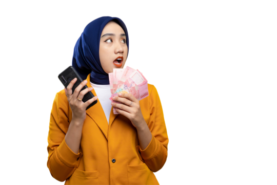 Shocked young Asian woman holding money and mobile phone, looking aside at copy space isolated on transparent background