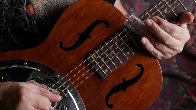 Male musician hand play Vintage Resonator acoustic dobro blues slide guitar.