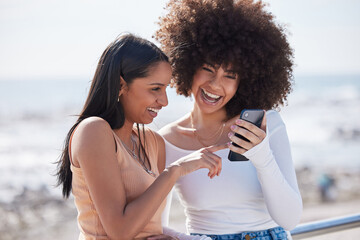 Girl friends, phone and laugh by the sea with text and meme on holiday with student travel in Miami. Mobile, app and gossip with funny women by the ocean online on the internet together in summer