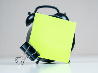 A blank reminder sticker and alarm clock inspire productivity, creating space for ideas and plans.