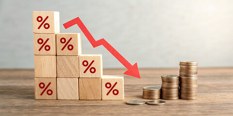 Conceptual image representing declining interest rates or financial loss. Wooden blocks with percentage symbols are stacked beside decreasing stacks of coins and a red downward arrow