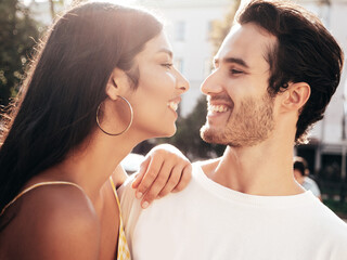 Smiling beautiful woman and her handsome boyfriend. Happy cheerful family. Sexy couple posing in the street at sunrise. During romantic date at sunny summer day outdoors. Looking at each other