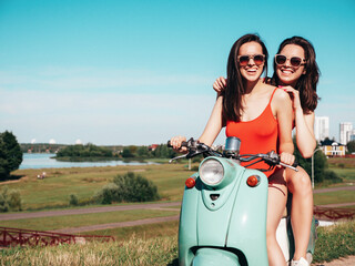 Two young beautiful smiling hipster female in summer red bathing suits. Sexy carefree women driving...