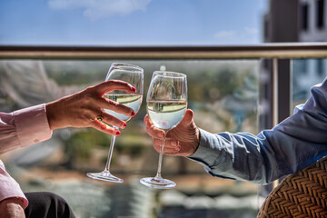 pensioners couple enjoying a glass of white white wine on the terrace of a flat, tourist holidaymakers pensioners enjoyment