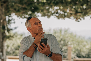 Middle-aged man looking at his phone with a thoughtful gesture