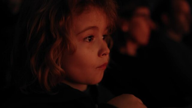 Child with popcorn in cinema watch movie. Kid in cinema theatre. Kid watching movie. Theater show for children. Movie premiere. Popcorn and happy kids face. Kids Movie. Closeup portrait of kid in