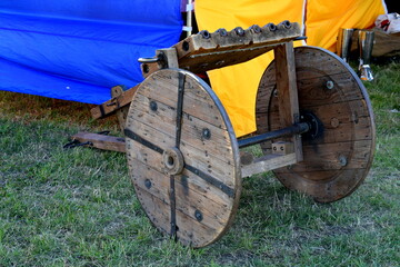 A view of a big multi barreled cannon, bombard or other artillery device on wheels with metal reinforcements located next to a colorful cloth tent seen in summer during a medieval festival in Poland