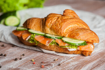 Croissant sandwiche with salmon and green parsley. Croissants with red fish on wooden cutting board. Healthy breakfast. Appetizer. Starter meal