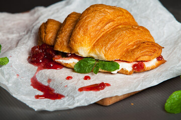 Croissant sandwiche with salmon and green parsley. Croissants with red fish on wooden cutting board. Healthy breakfast. Appetizer. Starter meal