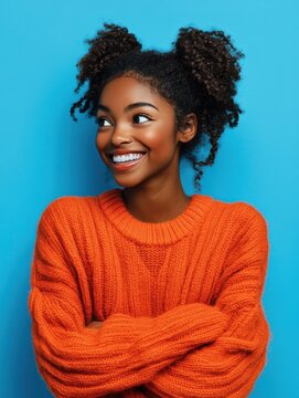 Happy emotions concept. Positive dark skinned beautiful young woman laughs poisitively looks aside with carefree face expression wears casual orange sweater isolated over blue studio background. illu