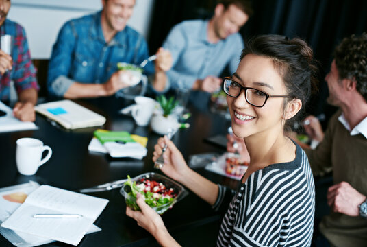 Meeting, smile and portrait of woman with salad in office for team building lunch for collaboration. Creative, happy and Asian female designer with colleagues eating healthy meal in workplace.
