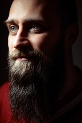 A close-up portrait of a bearded man in subdued lighting, capturing natural skin textures and...