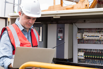 Electrician, Construction site. Electrical circuit board in console cabinet. Electrician using...
