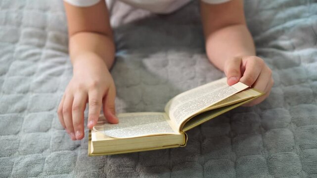 book in boy's hands. close-up view from above. turns pages