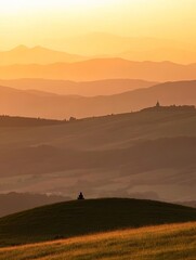 Serene Sunset Silhouette: A Meditative Moment Amidst Rolling Hills and Golden Hues