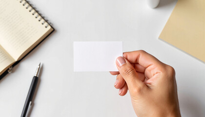 Obraz premium Blank Card Mockup - Hand Holding Card Above Desk with Notepad 