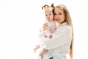 a mother with a baby daughter, a mother gently hugs her baby girl kissing, maternal love and care, a happy family with a baby on a white isolated background, a place for text