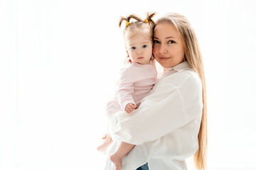 a mother with a baby daughter, a mother gently hugs her baby girl kissing, maternal love and care, a happy family with a baby on a white isolated background, a place for text