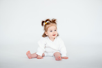 a baby girl on a white isolated background, a small child in a white knitted sweater smiling, a place for text