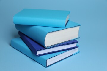 Stack of colorful books on light blue background, closeup