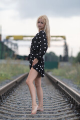 Obraz premium Portrait of a young beautiful blonde girl on an abandoned railroad.