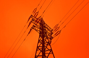 A lattice metal tower of a high voltage power line against an ominous red sky. An image on the theme of the energy crisis. Power and energy issues