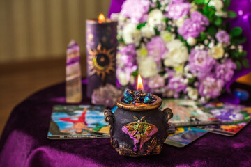A mystical flatlay with a soft purple bouquet, glowing candles, healing crystals and stylish...