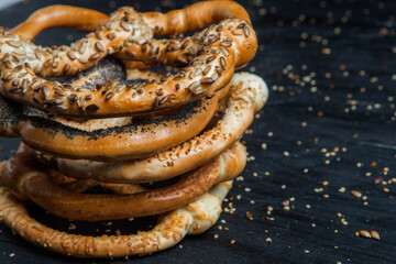 Fresh prepared homemade soft pretzels. Different types of baked pretzels with seeds on a black background