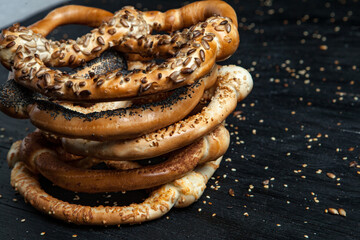 Fresh prepared homemade soft pretzels. Different types of baked pretzels with seeds on a black background