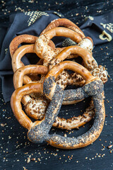 Fresh prepared homemade soft pretzels. Different types of baked pretzels with seeds on a black background