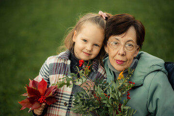 A warm family moment captured outdoors: a grandmother lovingly embraces her two young...