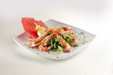 grilled prawns with rocket, lemon and olive oil on a white plate. Dish on a white background.