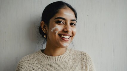 A happy woman applying a face mask, with a joyful smile on her face. Beauty and skincare theme.