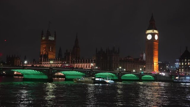 Big Ben and the Houses of Parliament glow at night in London. Westminster Bridge spans the River Thames, reflecting vibrant lights on its surface.