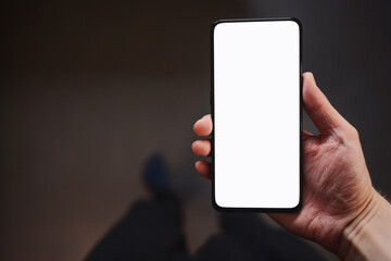 Man hold smartphone with white screen in his hand standing indoors in home environment