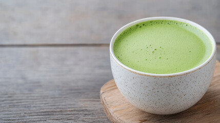 Creamy green matcha tea in speckled cup on wooden surface evokes tranquility and warmth