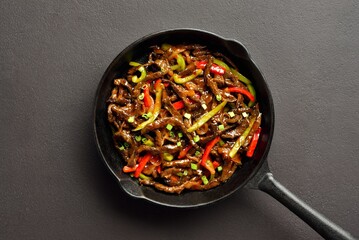 Fried thinly sliced beef steak with peppers in cast iron skillet