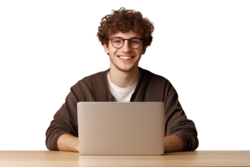 A happy young man with glasses and curly hair is sitting at a table in front of his laptop, against a transparent background