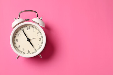 White alarm clock on pink background, top view. Space for text